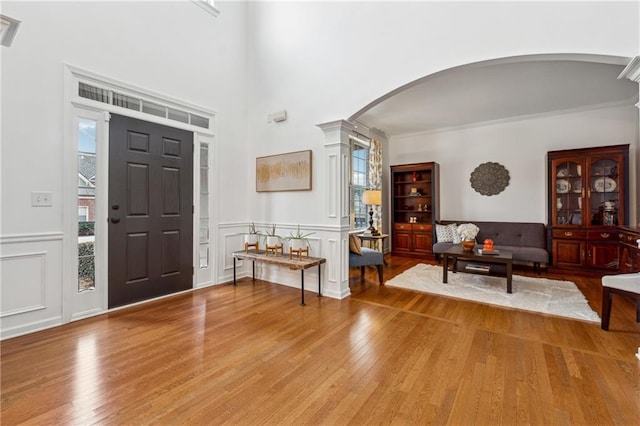 entrance foyer featuring crown molding, wood-type flooring, and decorative columns