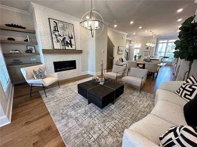 living room featuring a fireplace, ornamental molding, hardwood / wood-style flooring, and a notable chandelier