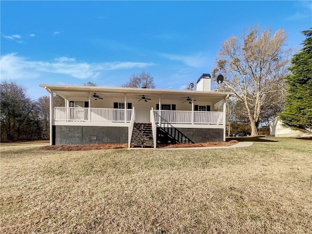 rear view of house with ceiling fan, stairway, a yard, and a chimney