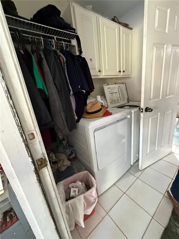 laundry area featuring cabinet space, washing machine and dryer, and light tile patterned floors