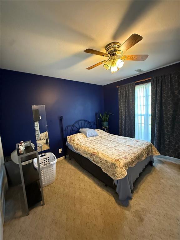 bedroom featuring baseboards, ceiling fan, visible vents, and carpet