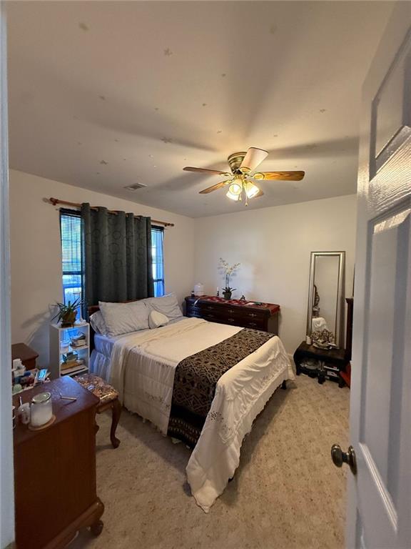 carpeted bedroom with visible vents and a ceiling fan
