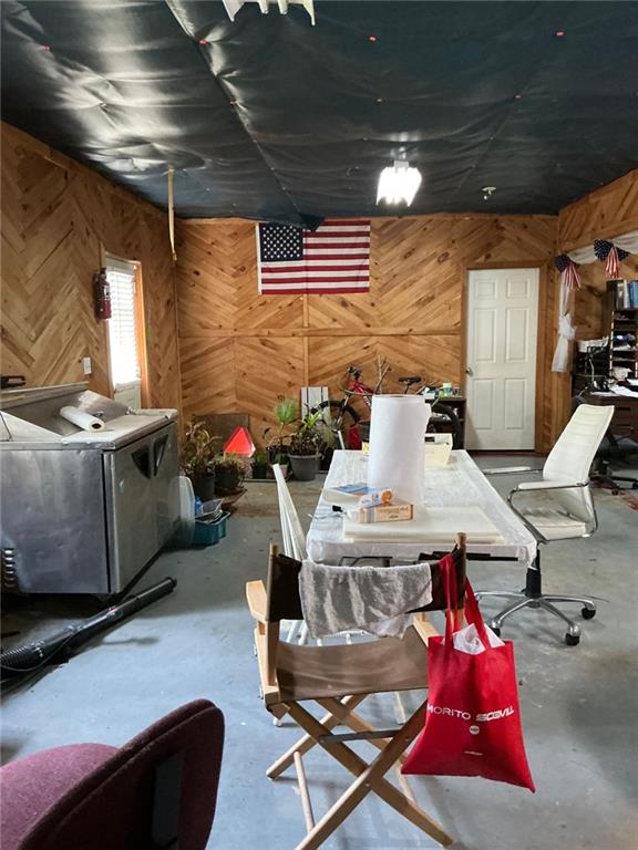 miscellaneous room featuring washer / dryer, concrete flooring, and wood walls