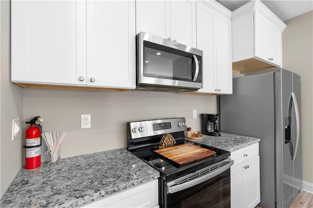 kitchen with light stone countertops, white cabinetry, and appliances with stainless steel finishes