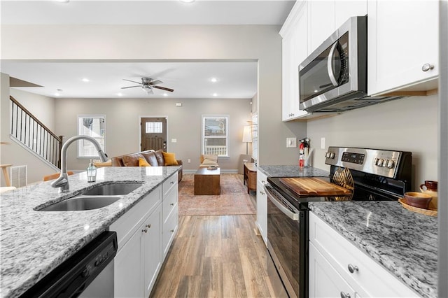 kitchen featuring sink, white cabinets, light hardwood / wood-style floors, stainless steel appliances, and light stone countertops