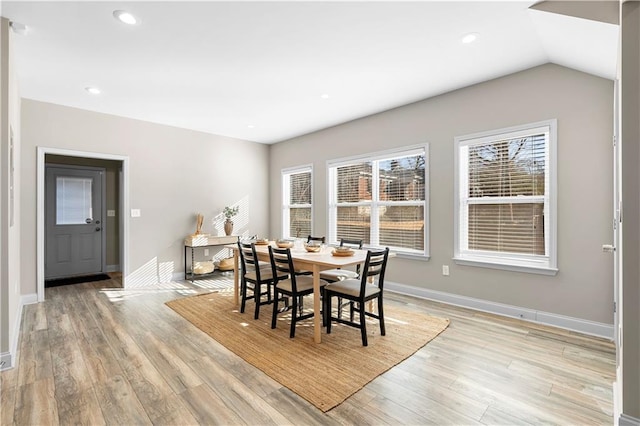 dining room with vaulted ceiling, plenty of natural light, and light hardwood / wood-style floors