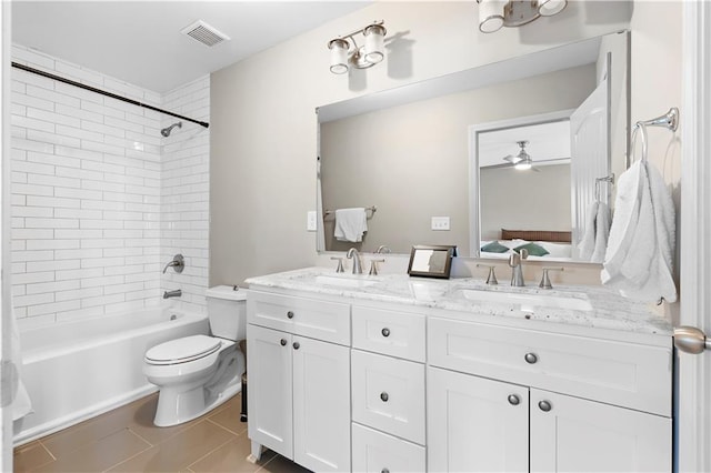 full bathroom featuring ceiling fan, tile patterned flooring, vanity, tiled shower / bath, and toilet