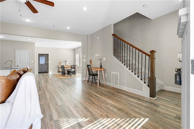 living room featuring ceiling fan, sink, and light hardwood / wood-style floors