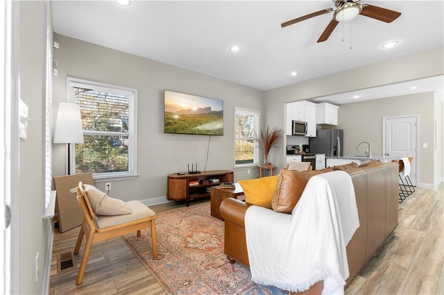 living room featuring sink, ceiling fan, and light hardwood / wood-style flooring