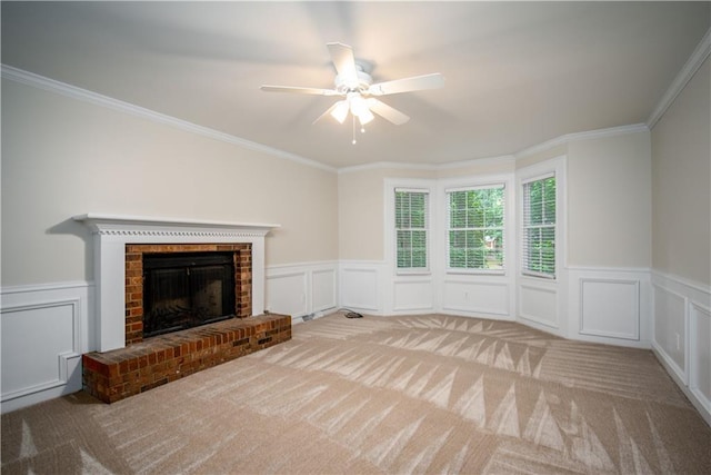 unfurnished living room with light carpet, ceiling fan, a brick fireplace, and crown molding