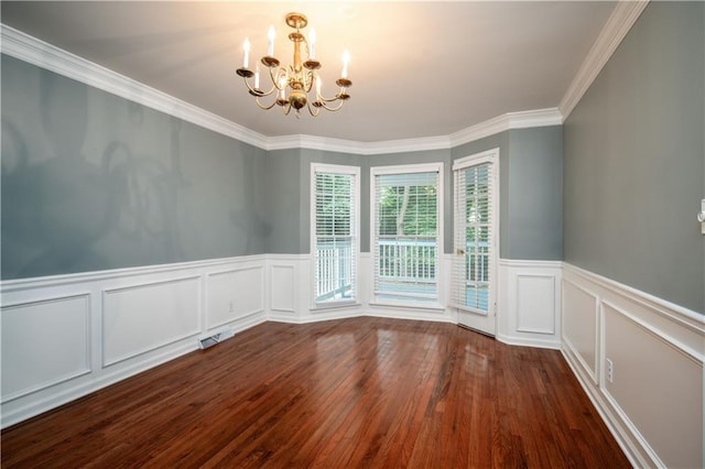 spare room featuring dark hardwood / wood-style flooring, ornamental molding, and a chandelier