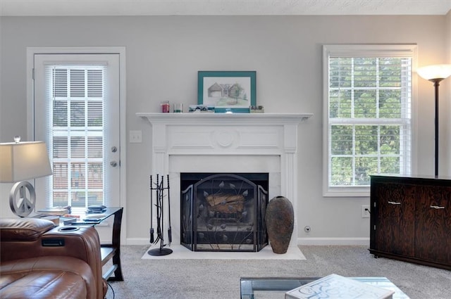 living area featuring baseboards, a fireplace with flush hearth, carpet, and a wealth of natural light