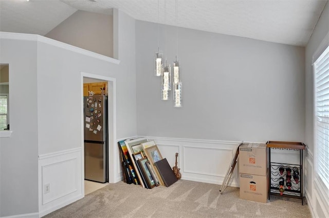 rec room with carpet, a decorative wall, lofted ceiling, and wainscoting