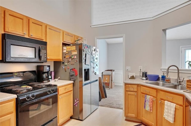 kitchen with light brown cabinets, light carpet, light countertops, a sink, and black appliances