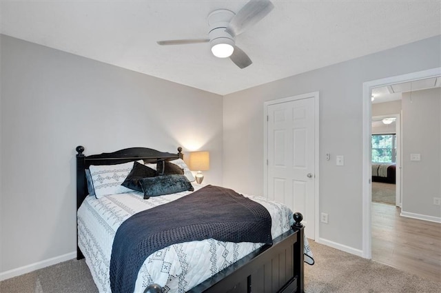 bedroom featuring a ceiling fan, baseboards, light carpet, and attic access