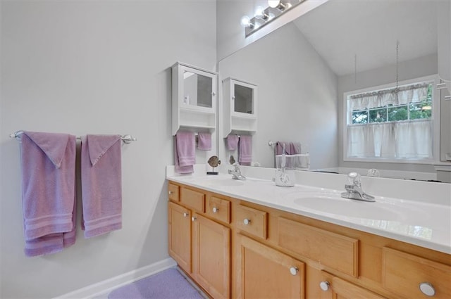 full bath featuring double vanity, baseboards, and a sink