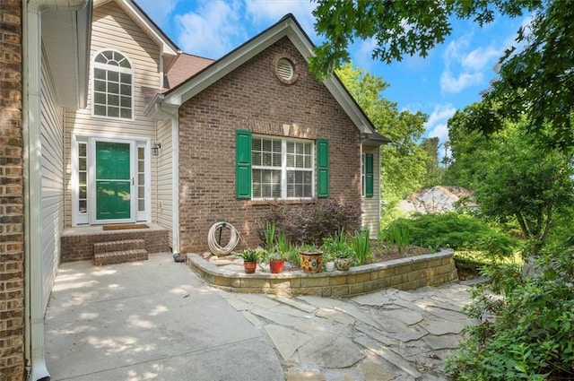 exterior space with brick siding, a patio area, and entry steps