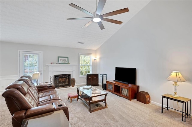 living room with ceiling fan, carpet, a fireplace with flush hearth, vaulted ceiling, and visible vents