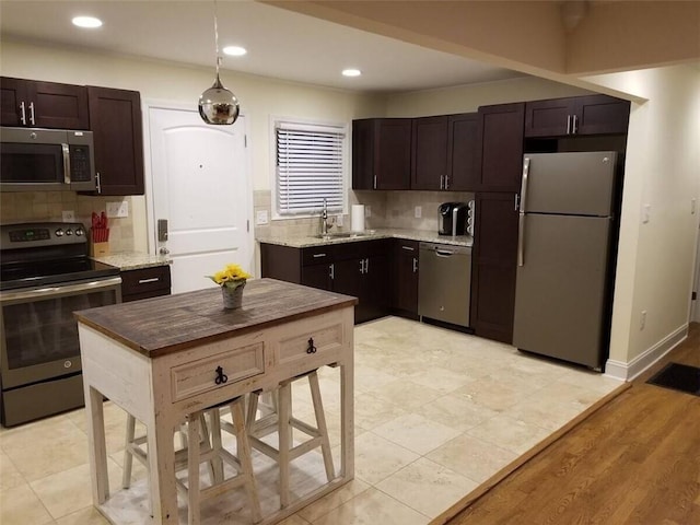 kitchen with pendant lighting, appliances with stainless steel finishes, light hardwood / wood-style floors, sink, and dark brown cabinetry