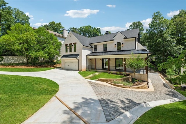 modern inspired farmhouse with metal roof, an attached garage, a standing seam roof, decorative driveway, and a front lawn