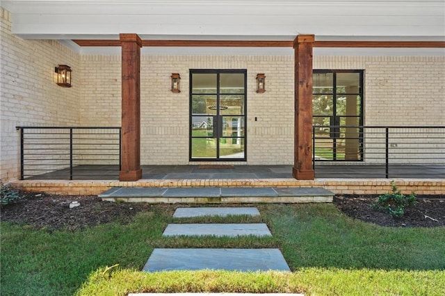 view of exterior entry featuring a porch and brick siding