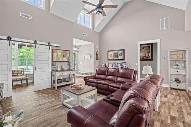 1423 Hillcrest Rd, Bowdon, GA 30108 - living room with high vaulted ceiling, a barn door, ceiling fan, wood finished floors, and plenty of natural light