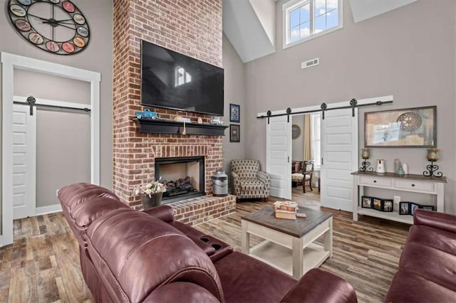 1423 Hillcrest Rd, Bowdon, GA 30108 - living room with a barn door, high vaulted ceiling, wood finished floors, a brick fireplace, and baseboards