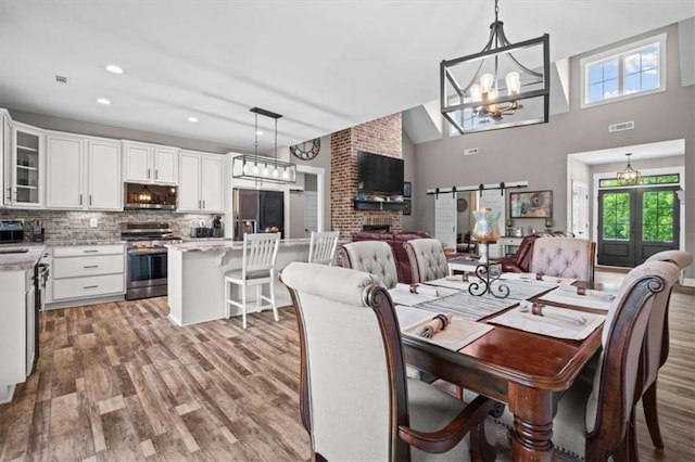 1423 Hillcrest Rd, Bowdon, GA 30108 - dining room featuring healthy amount of natural light, wood finished floors, a chandelier, french doors, and a towering ceiling