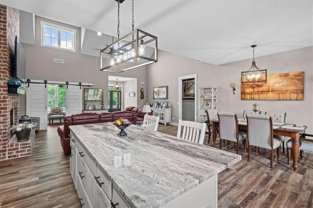 1423 Hillcrest Rd, Bowdon, GA 30108 - kitchen featuring a chandelier, dark wood finished floors, a barn door, hanging light fixtures, and light stone countertops