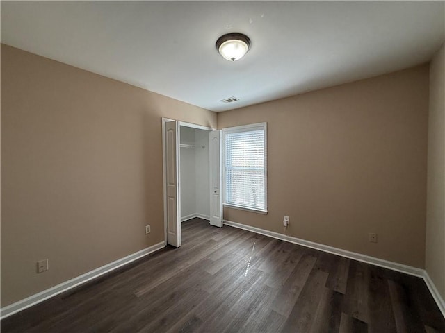 2728 Sandalwood Cir, Locust Grove, GA 30248 - unfurnished bedroom featuring dark wood-style floors, visible vents, a closet, and baseboards