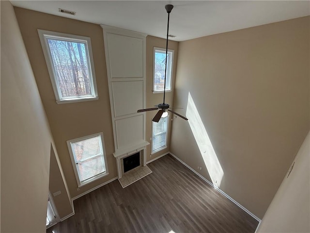 2728 Sandalwood Cir, Locust Grove, GA 30248 - unfurnished living room with dark wood-style floors, baseboards, visible vents, a ceiling fan, and a fireplace