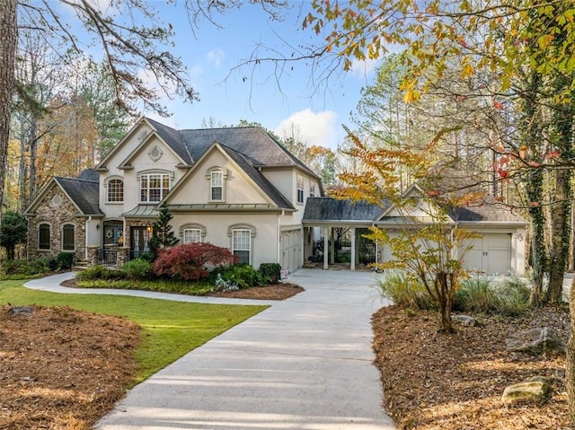 french country home featuring stucco siding, concrete driveway, a standing seam roof, a garage, and a front lawn
