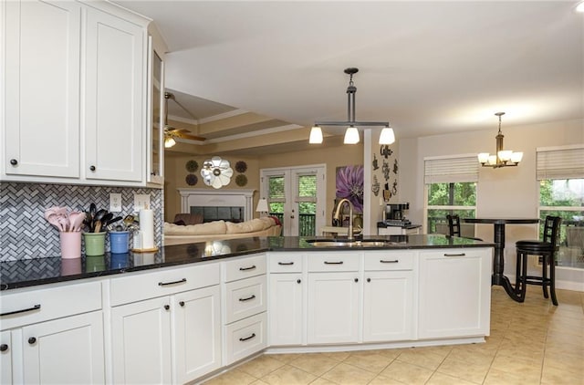 kitchen featuring plenty of natural light, a sink, decorative backsplash, and ceiling fan with notable chandelier