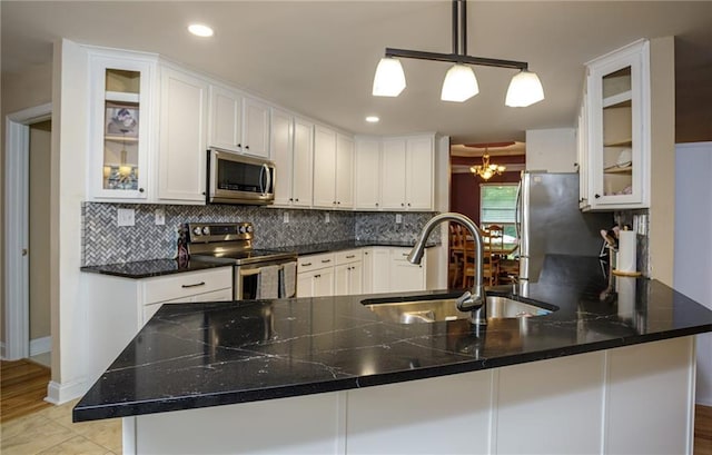 kitchen with tasteful backsplash, appliances with stainless steel finishes, white cabinets, and a sink