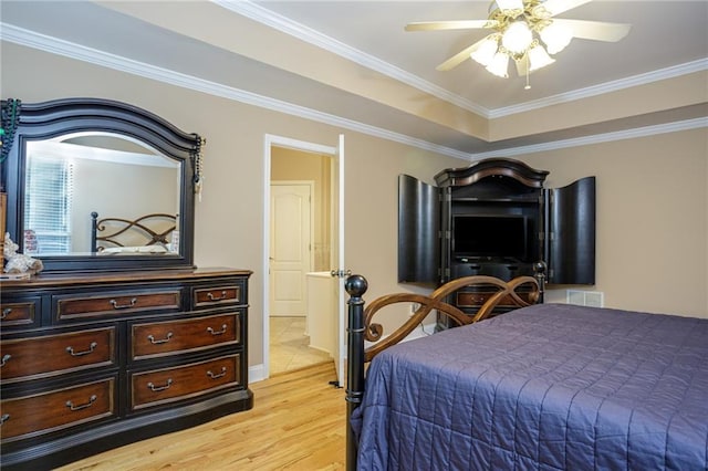 bedroom featuring a tray ceiling, crown molding, light wood-style flooring, and ceiling fan