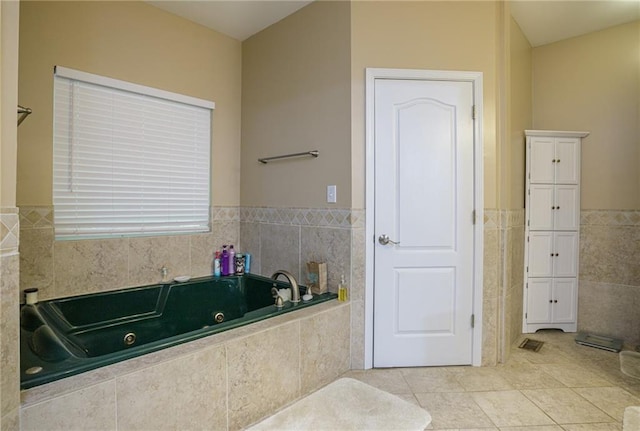 full bath featuring tile patterned flooring, wainscoting, tile walls, and a whirlpool tub