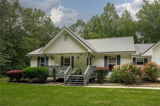 ranch-style house with metal roof, a porch, a front lawn, and a ceiling fan