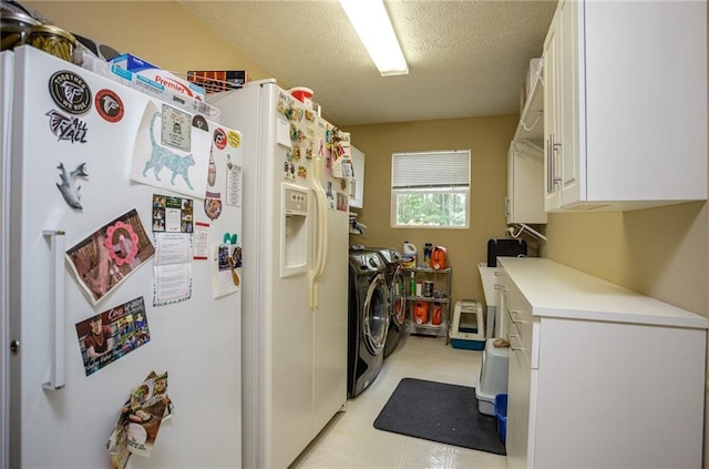 laundry area featuring cabinet space, separate washer and dryer, a textured ceiling, and light floors