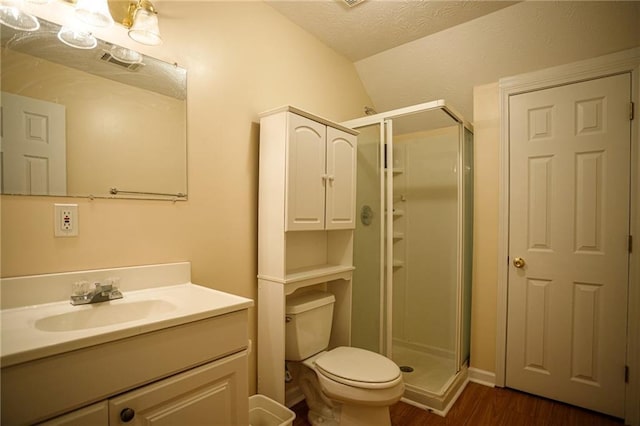 bathroom featuring toilet, a stall shower, a textured ceiling, and wood finished floors