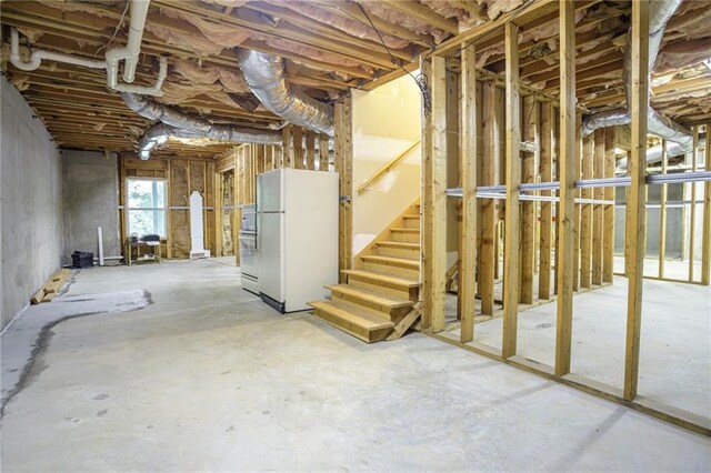 unfinished basement featuring freestanding refrigerator