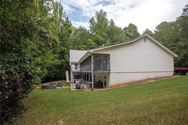 rear view of property featuring a sunroom, a hot tub, a patio, and a yard