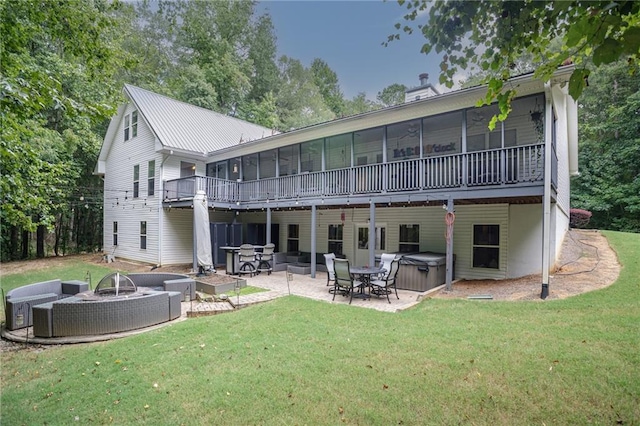 rear view of house with a fire pit, a sunroom, a lawn, a patio area, and a hot tub