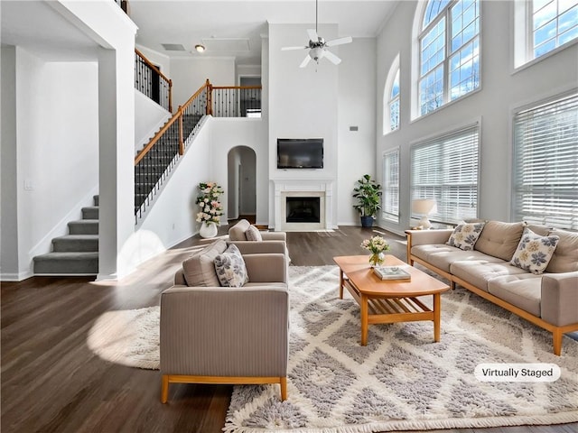 living area with plenty of natural light, a fireplace with flush hearth, stairway, and wood finished floors