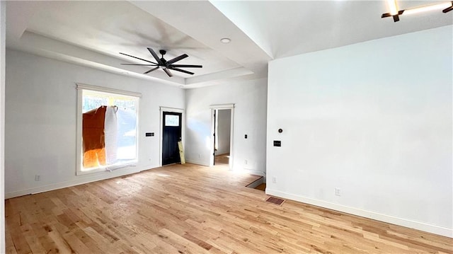 unfurnished room featuring light hardwood / wood-style floors, a raised ceiling, and ceiling fan