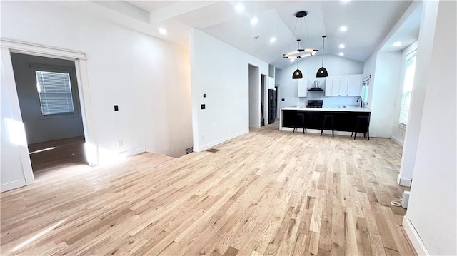 unfurnished living room featuring sink, high vaulted ceiling, and light hardwood / wood-style flooring