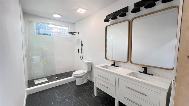 bathroom featuring a tile shower, vanity, and toilet