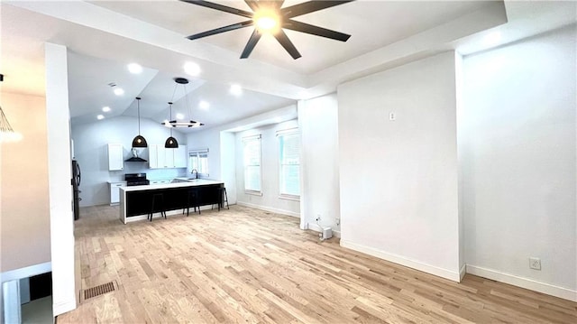 kitchen with light wood-type flooring, ceiling fan, pendant lighting, white cabinets, and a center island