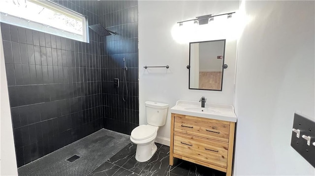 bathroom featuring vanity, toilet, and a tile shower