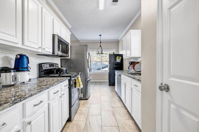 kitchen featuring decorative light fixtures, white cabinetry, dark stone countertops, ornamental molding, and stainless steel appliances