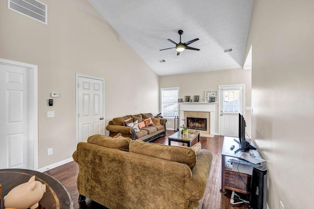 living room featuring dark hardwood / wood-style flooring, high vaulted ceiling, a high end fireplace, and ceiling fan